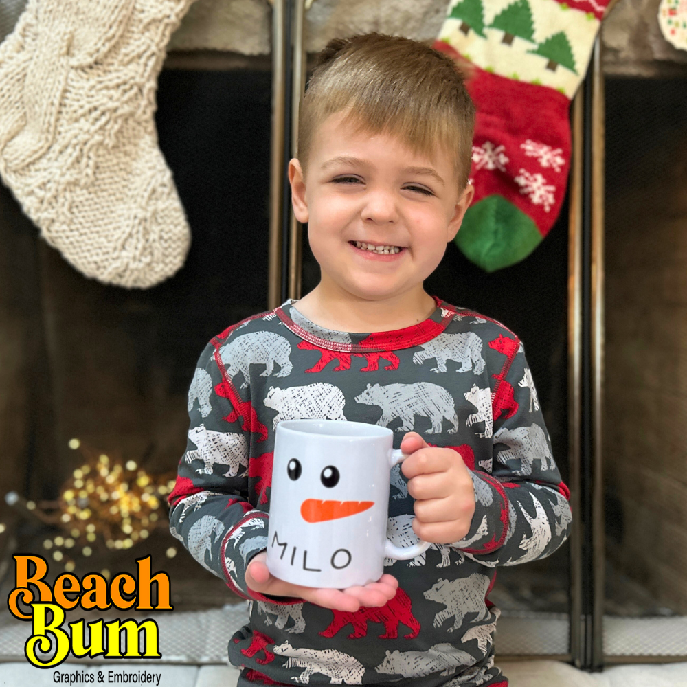 A young boy holding a personalized Christmas mug by a warm fireplace, showcasing a joyful holiday moment with a custom-designed mug in hand, radiating festive warmth and cheer.